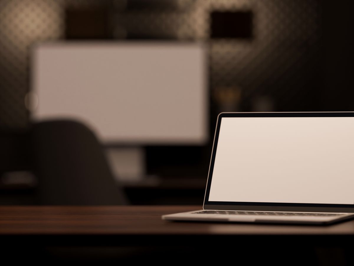 A laptop on a desk in a dark, modern office