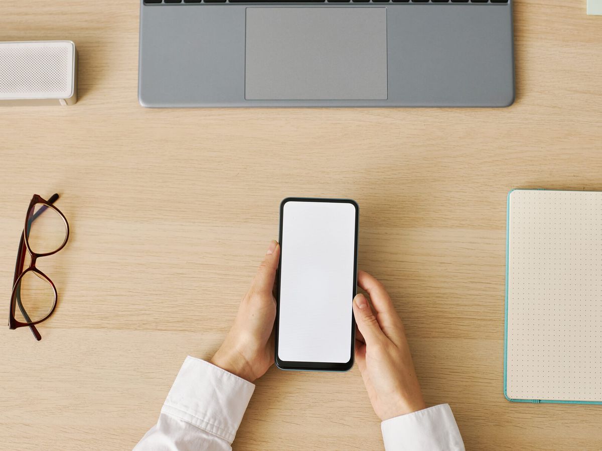 A business smartphone in hand on a clean desk